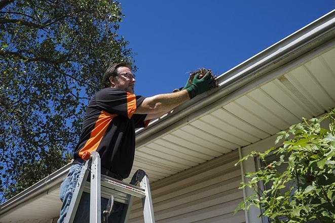 a worker inspecting and repairing a clogged gutter in Fellsmere, FL